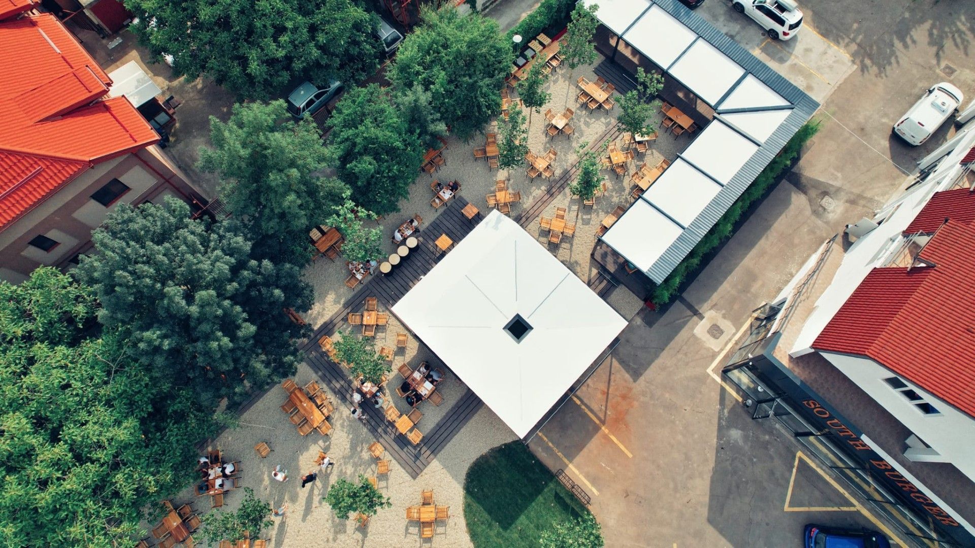 Restaurant SouthBurger — vedere aeriană a terasei, umbrar alb pătrat cu oculus și copertine retractabile