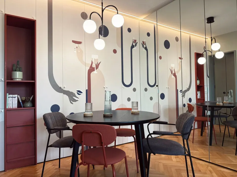 Apartament C9 — masă rotundă neagră în fața peretelui de dulapuri cu tapet Vladila personalizat și nișă bordo cu rafturi